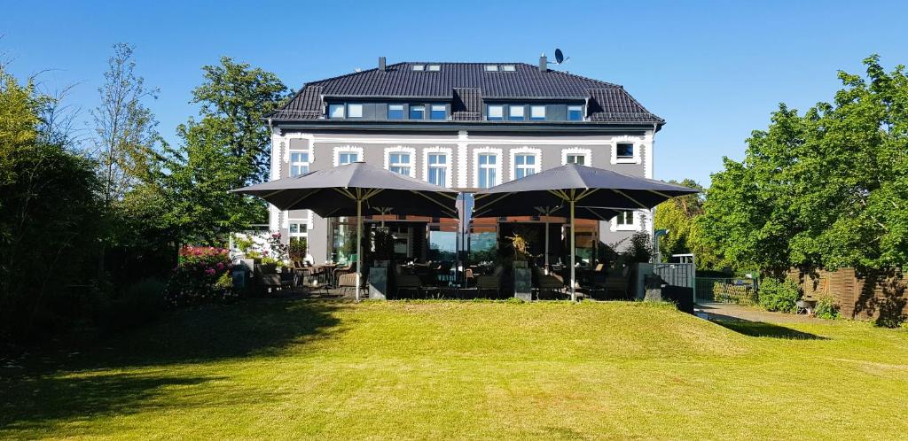 duży biały dom z parasolem na dziedzińcu w obiekcie Lounge-Hotel Seeterrassen w mieście Wandlitz