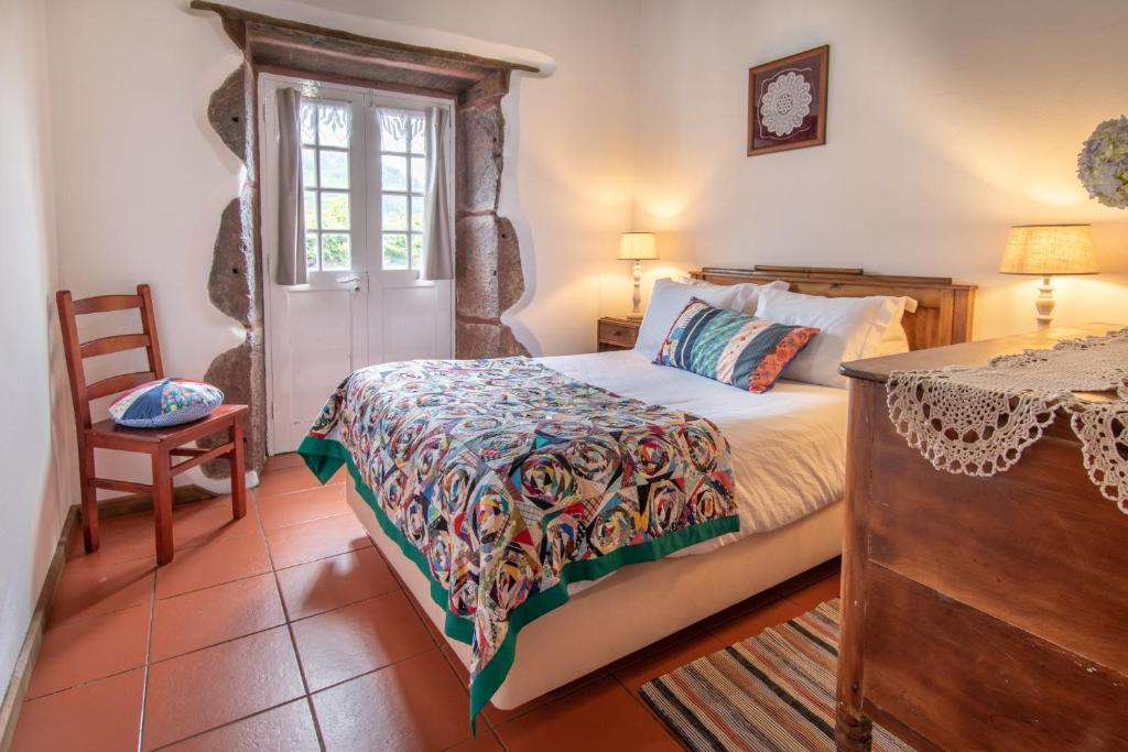 a bedroom with a bed and a table and a chair at Aldeia da Cuada in Faja Grande