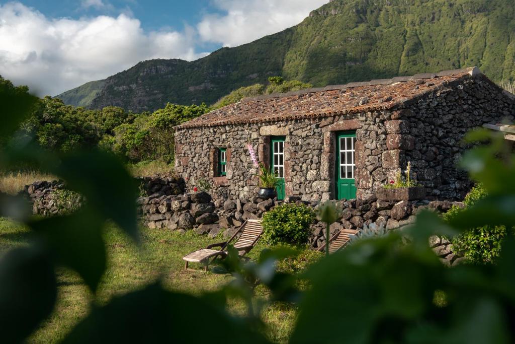 a stone house with a mountain in the background at Aldeia da Cuada in Faja Grande