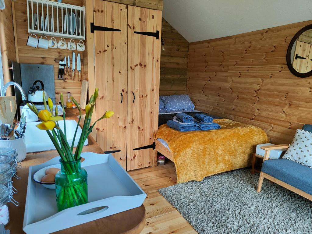 Dryw bach glamping hut في ولياندايلو: غرفة نوم مع سرير و مزهرية من الزهور على طاولة