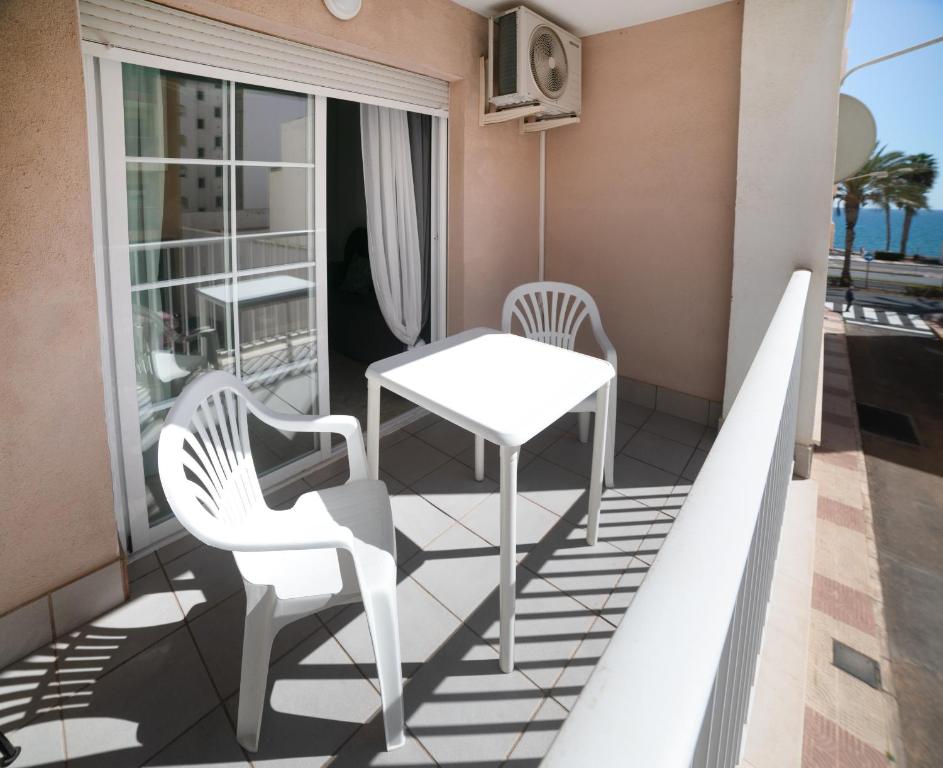 Balcón con 2 sillas, mesa y mesa en Apartamento con piscina y terraza a 50 metros de la playa, en Roquetas de Mar