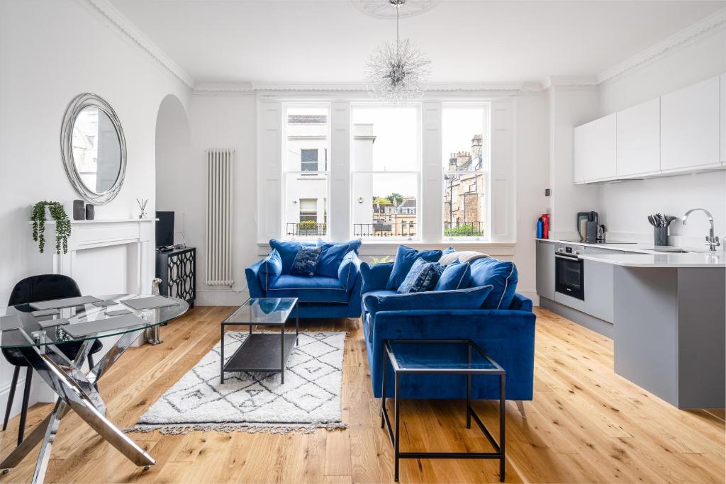 a living room with blue couches and a kitchen at River Street View in Bath