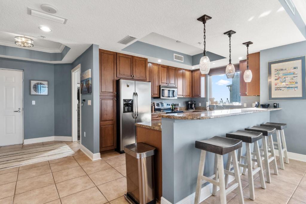 a kitchen with wooden cabinets and a bar with stools at Santo Amaro 801B - Lost Key Golf & Beach in Perdido Key