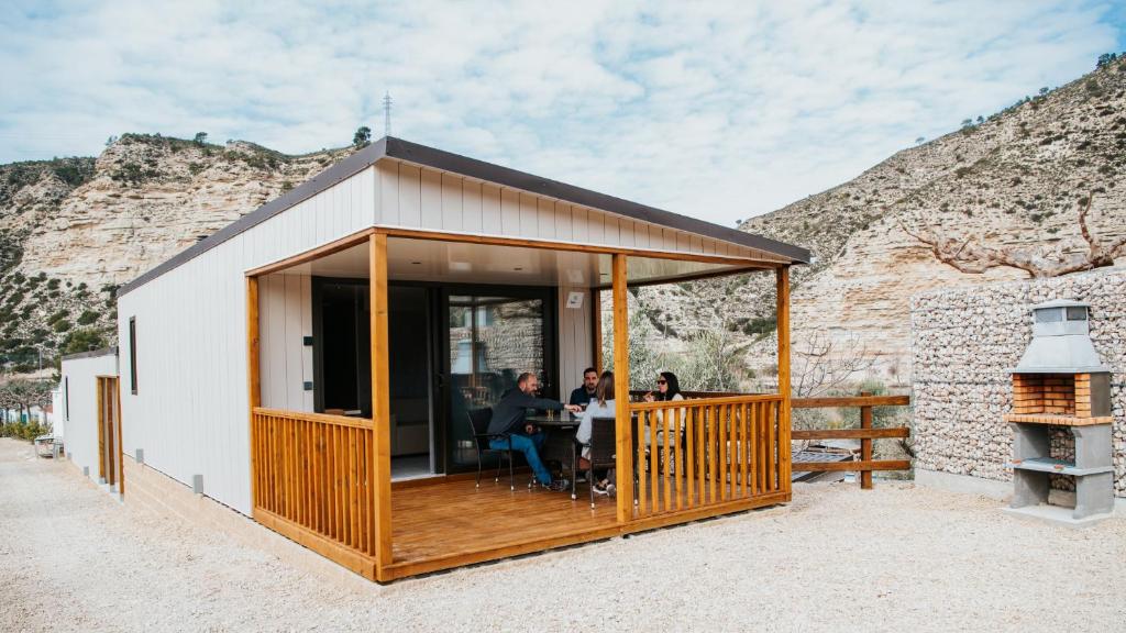 uma casa com um deque com pessoas sentadas à mesa em Camping Port Massaluca em Pobla de Masaluca