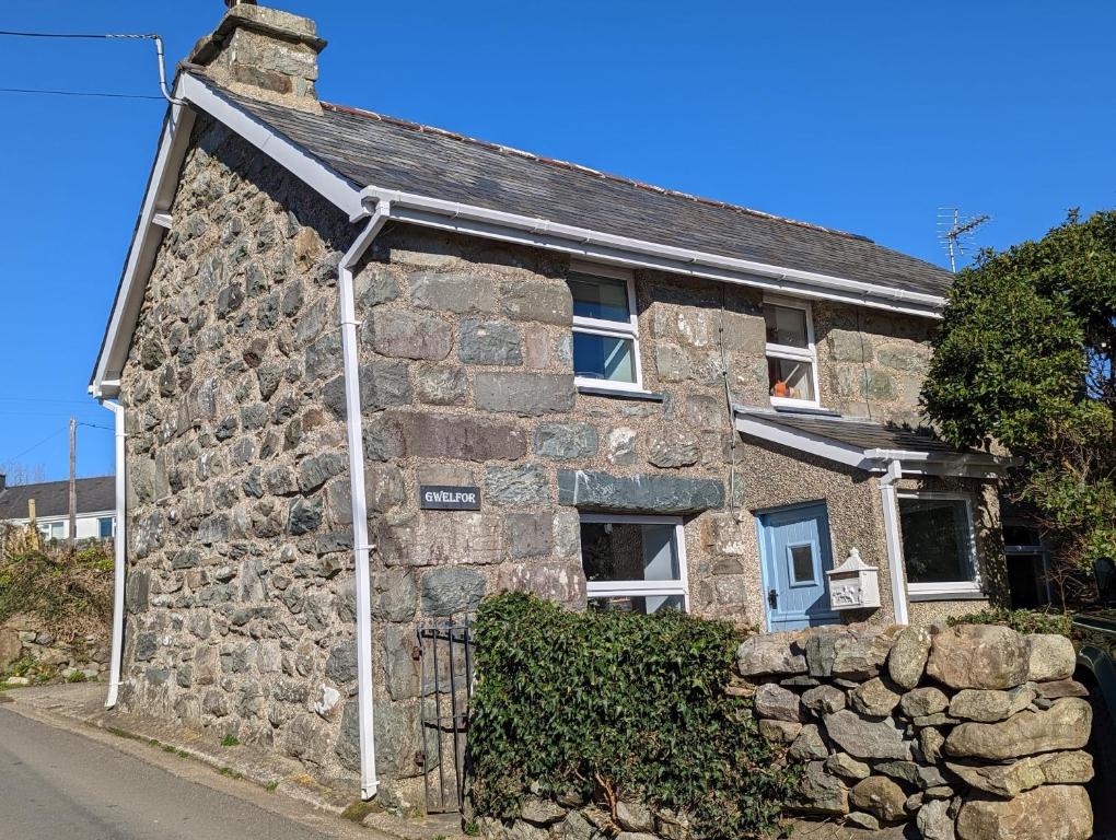 uma antiga casa de pedra com uma parede de pedra em Cosy, coastal cottage in Snowdonia em Harlech