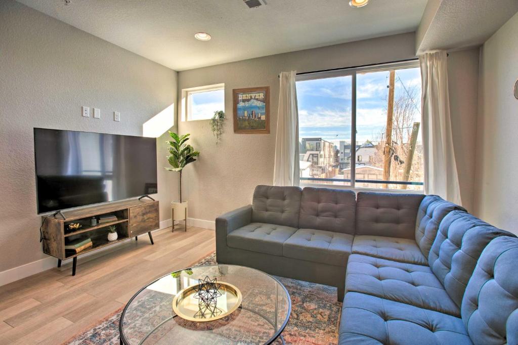 a living room with a blue couch and a tv at Modern Townhome with Rooftop Hot Tub and Mtn View in Denver