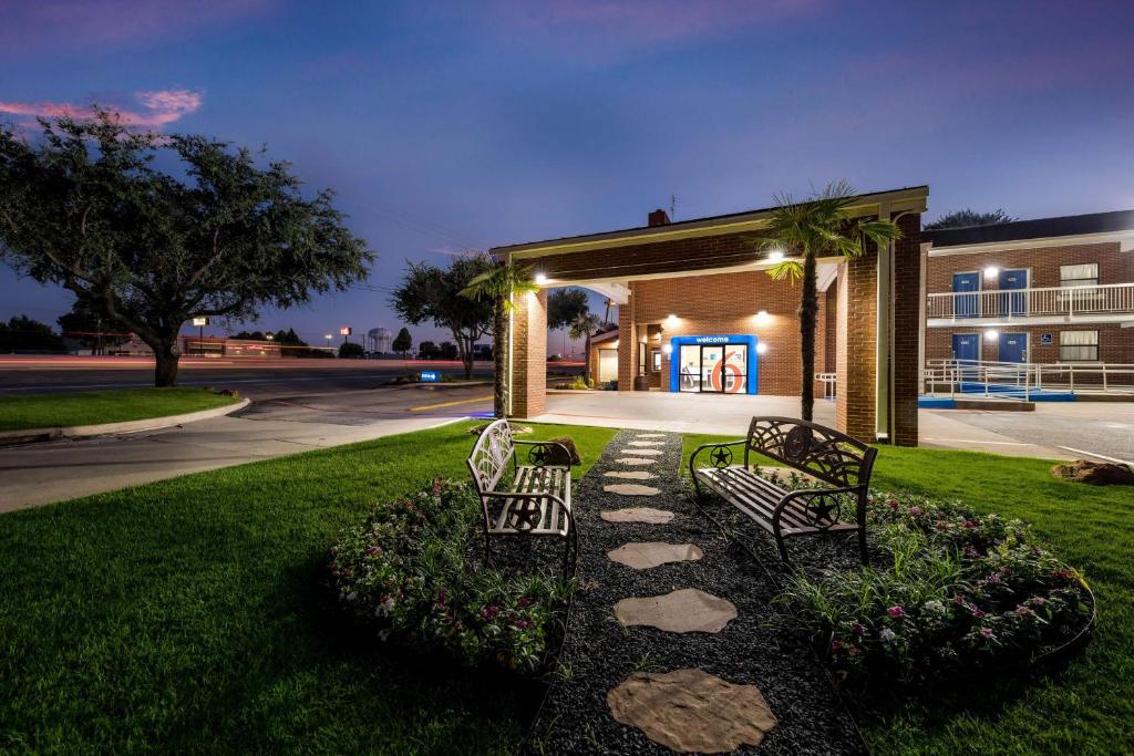 dos bancos sentados frente a un edificio por la noche en Motel 6-Plano, TX - Plano Northeast, en Plano