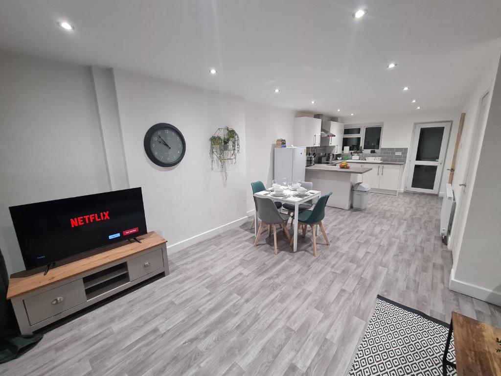 a living room with a television and a table with chairs at 6 Bed sleeps 7, 1 mile from M54 i54 Jaguar Land Rover MOOG in Wolverhampton