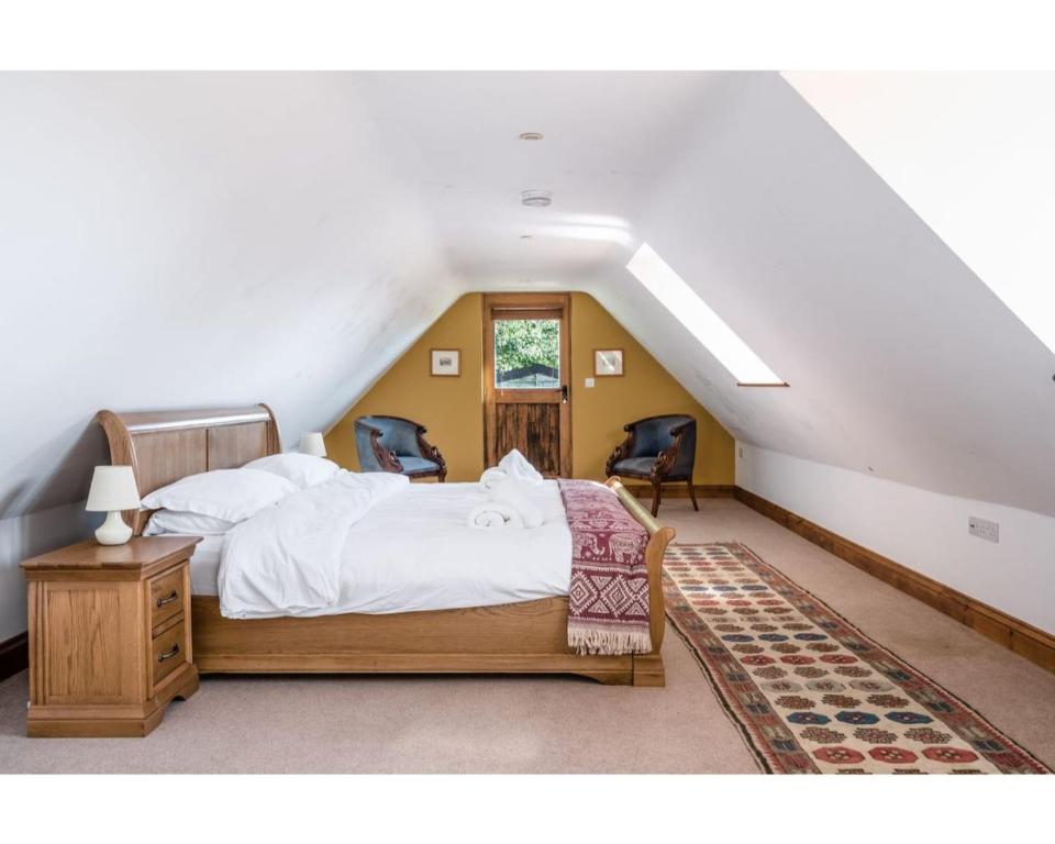 a bedroom with a bed and two chairs in a attic at Huish Lodge in Radstock