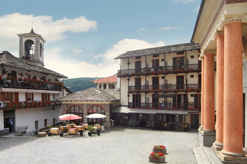 een binnenplaats van een gebouw met tafels en parasols bij Albergo Miniere in Traversella