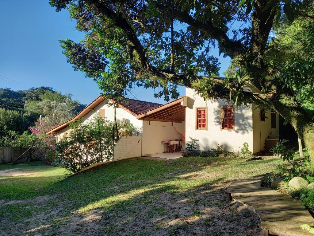 ein weißes Haus mit einem Baum davor in der Unterkunft Morada Caminho do Mar in Praia do Rosa