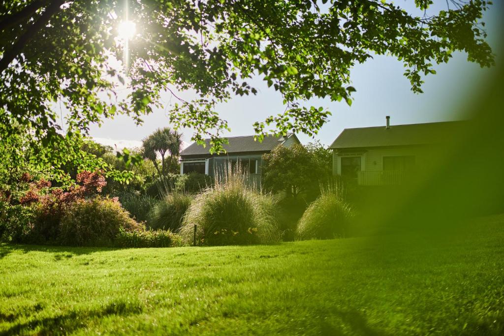 a house in a green yard with the sun shining at Parehua Resort in Martinborough 