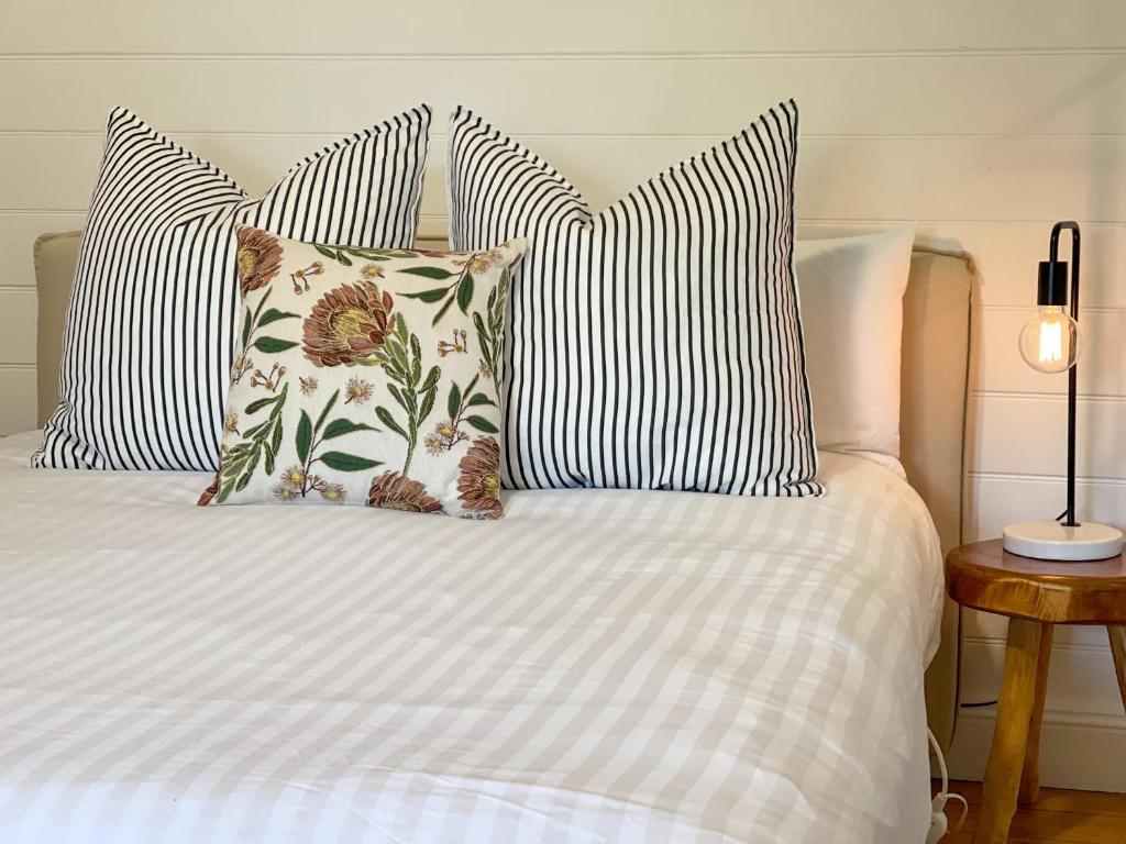 a bed with four pillows on it with a white bed at Blue Duck Cottage Village Comfort with Fireplace in Tenterfield