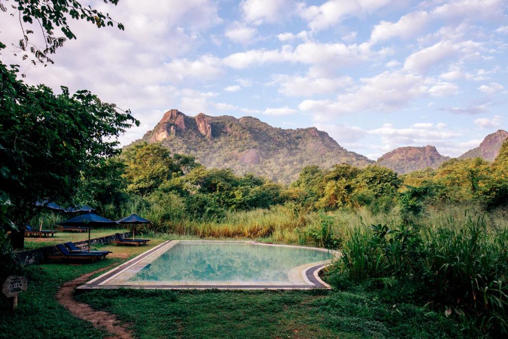 a swimming pool with mountains in the background at Gal Oya Lodge in Galgamuwa