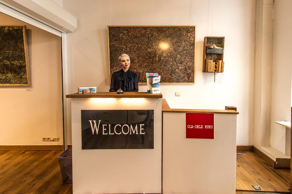 ブリュッセルにあるレントバイナイト アパートホテルの歓迎の看板を持つ表彰台に立つ男