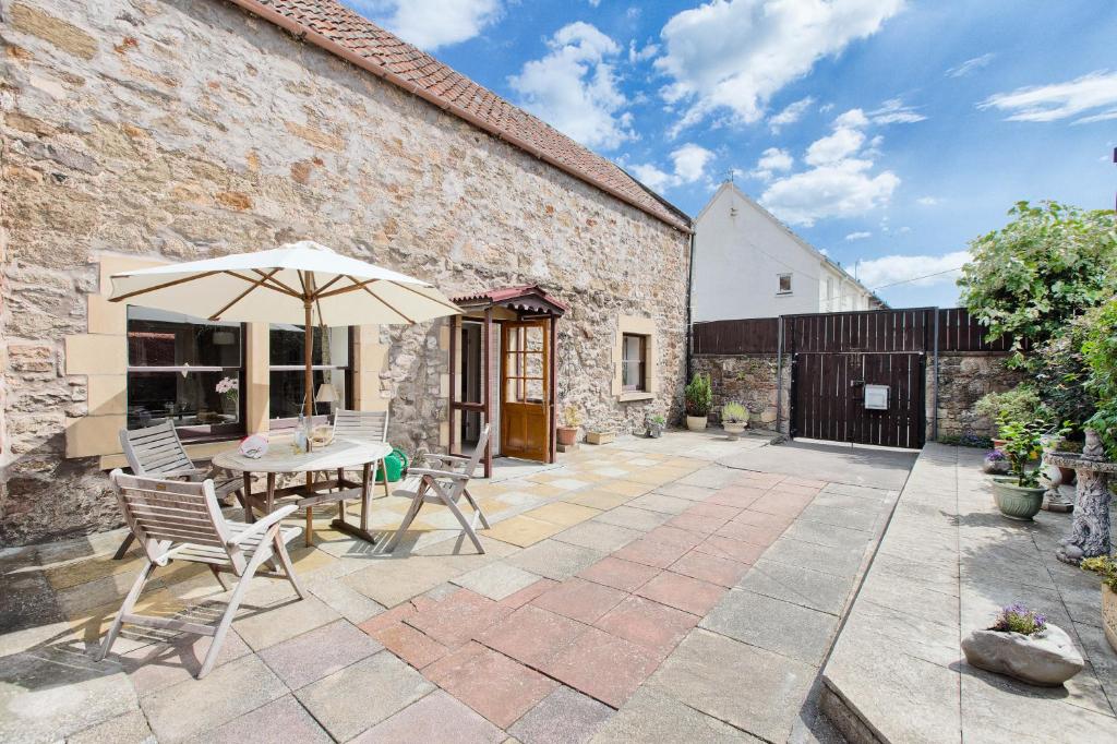 an outdoor patio with a table and an umbrella at Painters Cottage in Haddington