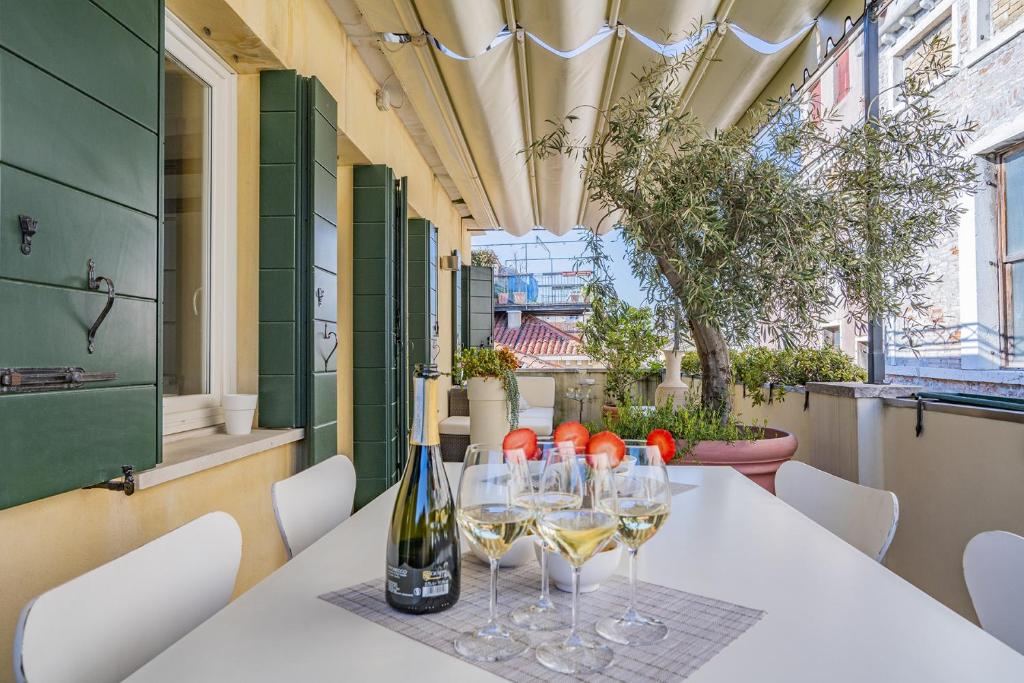 a table with wine glasses and bottles on it at Colleoni Apartment with 2 Superb Terraces in Venice
