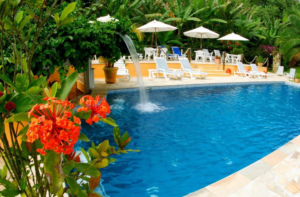 a swimming pool with chairs and a fountain at Hotel Ilhasol in Ilhabela
