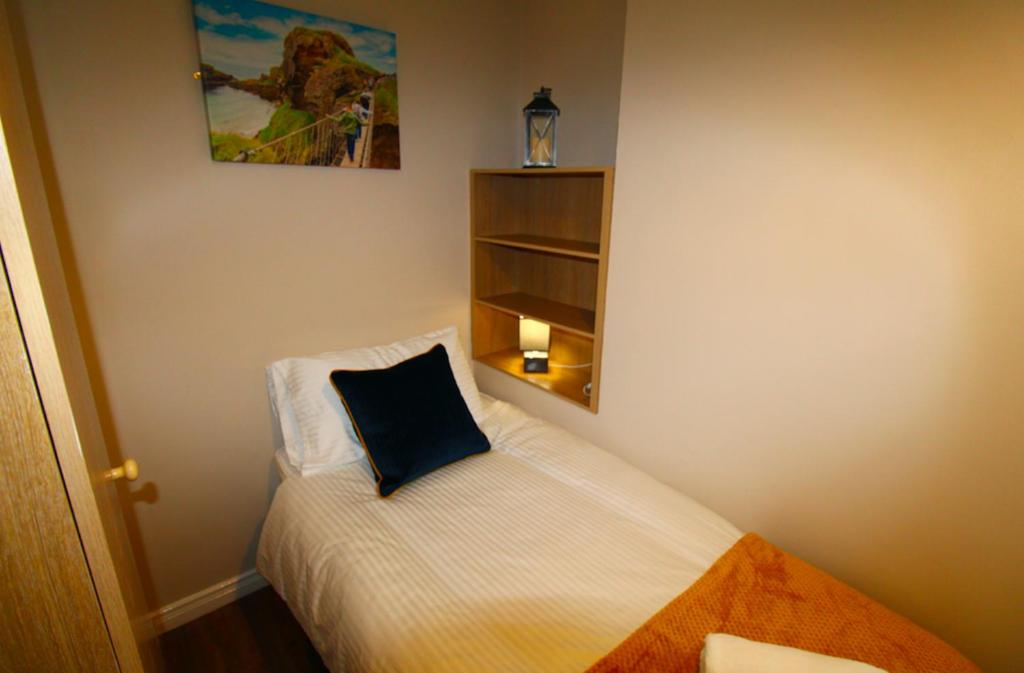 a bedroom with a bed with a blue pillow on it at Beulah Guest House in Portrush