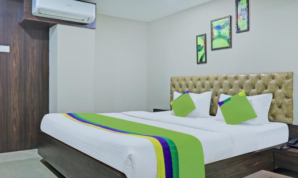 a bedroom with a white bed with a green blanket at Treebo Trend Raj Inn Lalpur in Rānchī