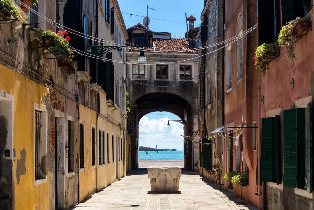 an alley with a view of the ocean through an arch at Bricola Biennale Apartments in Venice