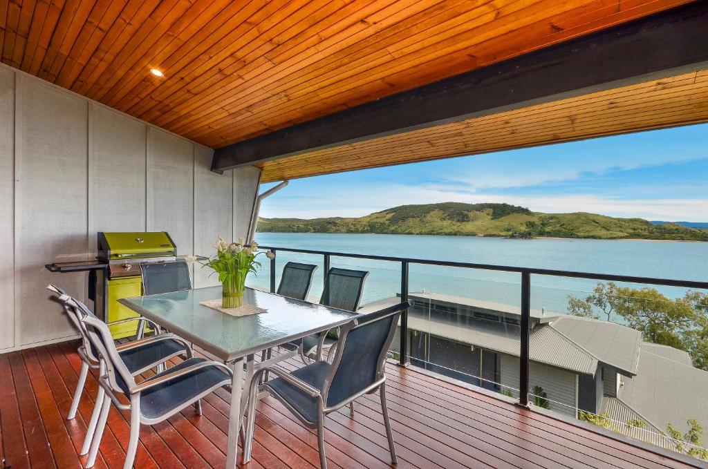 a table and chairs on a deck with a view of the water at Sea View Shorelines Hamilton Island in Hamilton Island