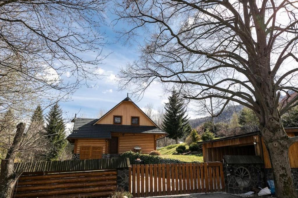 uma casa de madeira com uma cerca em frente em Očarujúci drevený dom v prírodnom prostredí em Kordíky