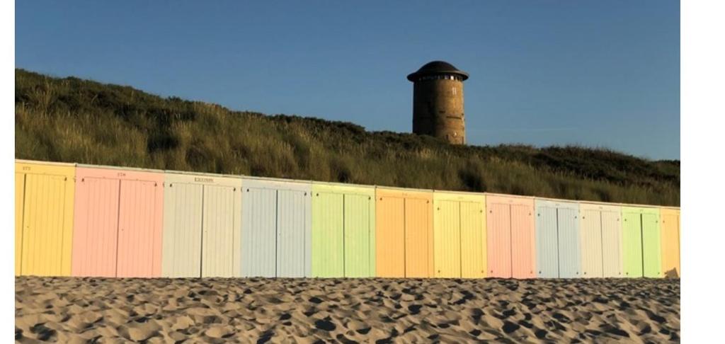 a colorful fence with a lighthouse in the background at Schitterend appartement HartVanDomburg in Domburg