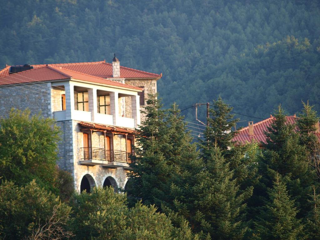 a building on top of a hill with trees at Παραδοσιακός Ξενώνας Βαμβακούς in Vamvakoú