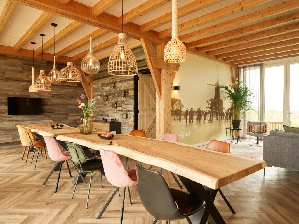 une salle à manger avec une grande table et des chaises en bois dans l'établissement Erfgoedpark De Hoop Vakantiewoningen, à Uitgeest
