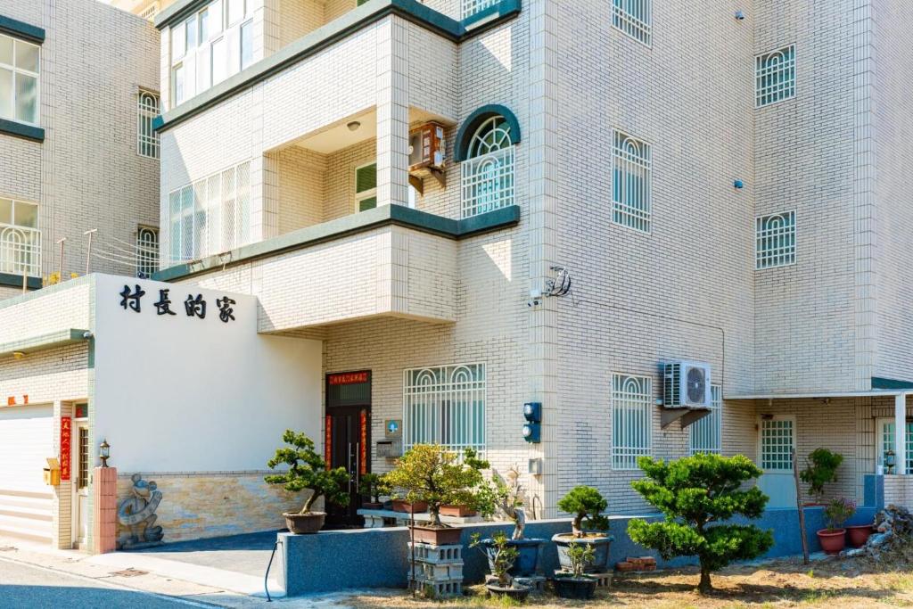 馬公市的住宿－村長的家民宿 The Village chiefs House，一座白色的大建筑,设有红色的门