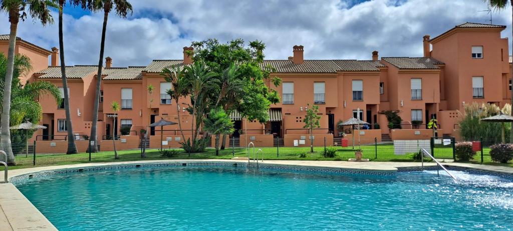 una grande piscina di fronte a un edificio di UNIFAMILIAR 3 D.NOVO SANCTI PETRI a Chiclana de la Frontera
