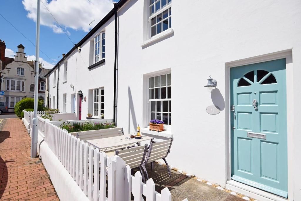 een wit huis met een blauwe deur en banken bij Seashell Cottage - Worthing in Worthing