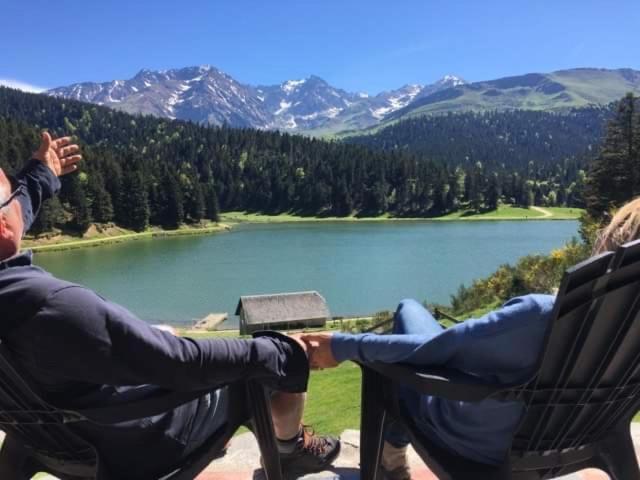 un hombre y una mujer sentados en sillas mirando un lago en Gite Du Montagnol A Payolle en Sainte-Marie-de-Campan