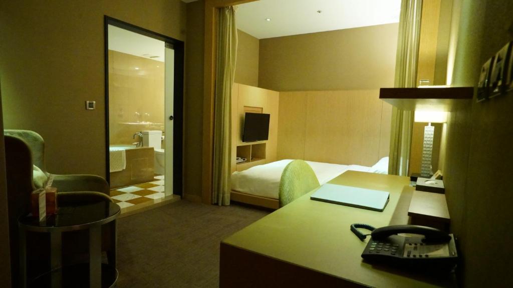 a hotel room with a bed and a desk at City Suites-Taipei Nanxi in Taipei