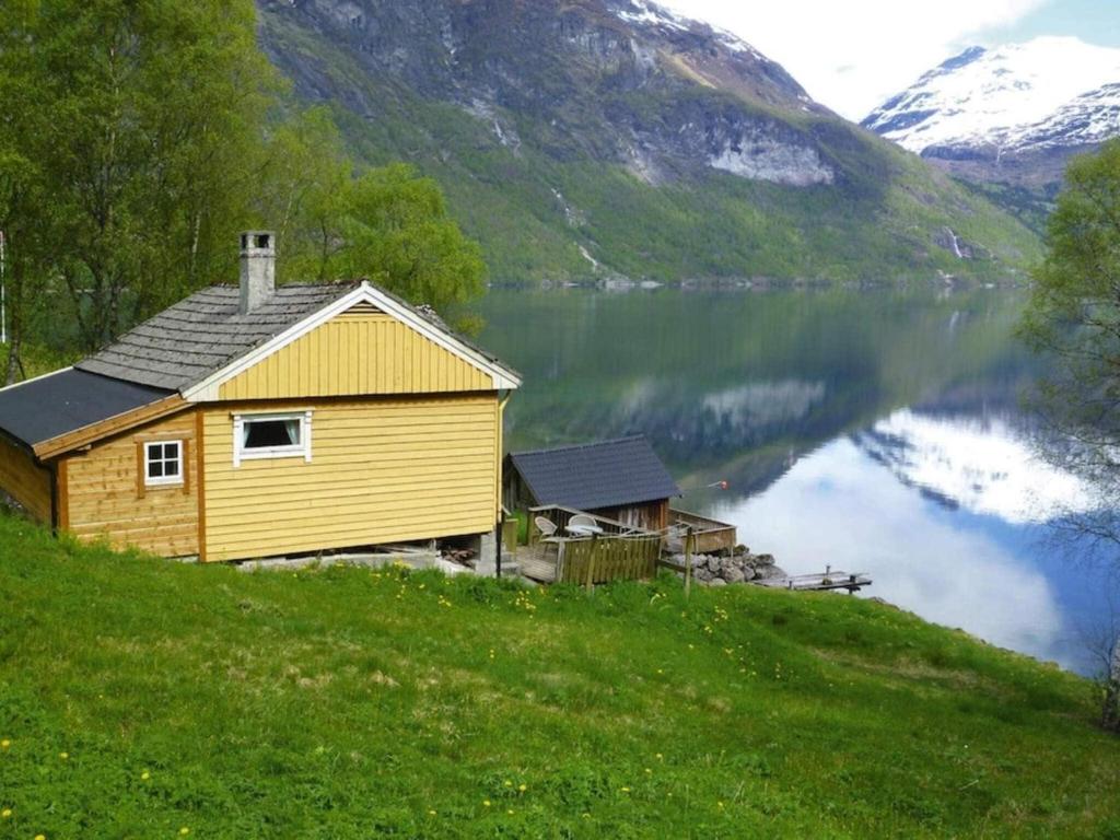 uma casa amarela numa colina ao lado de um lago em Holiday home STRYN III em Stryn