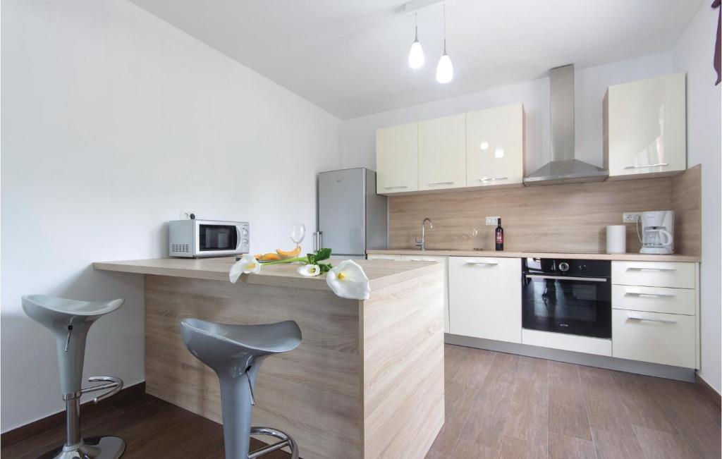 kuchnia z białymi szafkami i blatem ze stołkami w obiekcie Holiday Home Marcana 57 w mieście Marčana