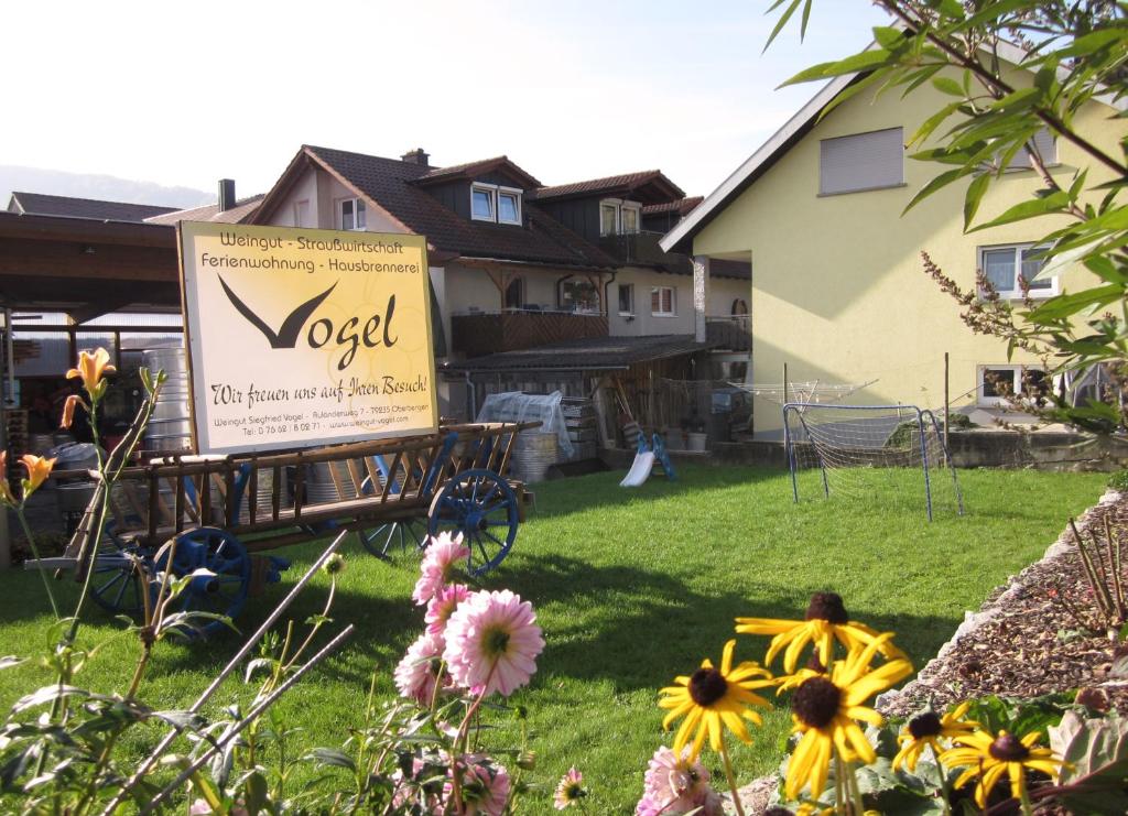 ein Schild im Hof eines Hauses mit Blumen in der Unterkunft Weingut & Straußwirtschaft Vogel in Vogtsburg