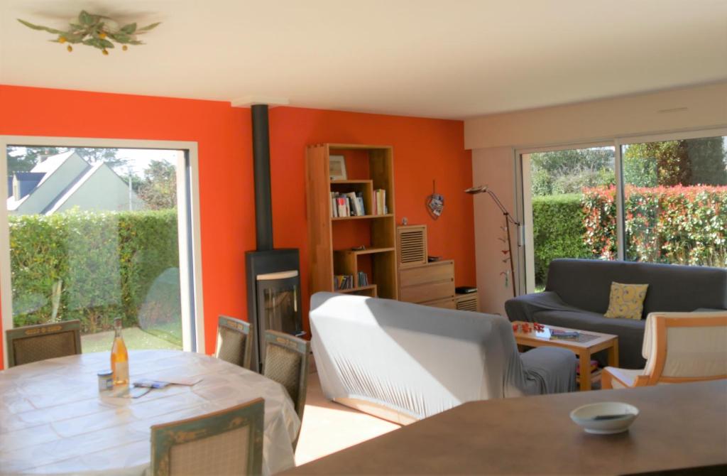ein Wohnzimmer mit orangefarbenen Wänden sowie einem Tisch und Stühlen in der Unterkunft * LA MIMOSA * MAISON 8 PERSONNES PROCHE PLAGE in Saint-Philibert