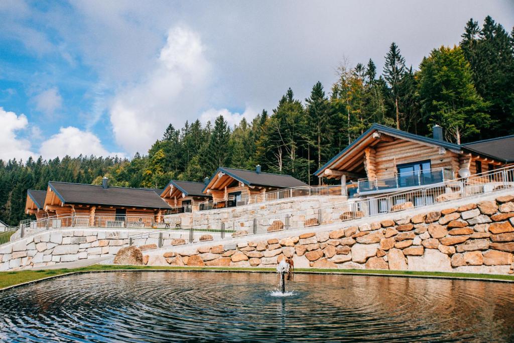 a lake in front of a log cabin at Blockhausen Luxus Chalets in Oberschwarzenberg