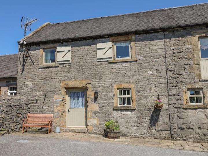 une vieille maison en pierre avec un banc et une porte dans l'établissement Wetton Barns Holiday Cottages, à Ashbourne
