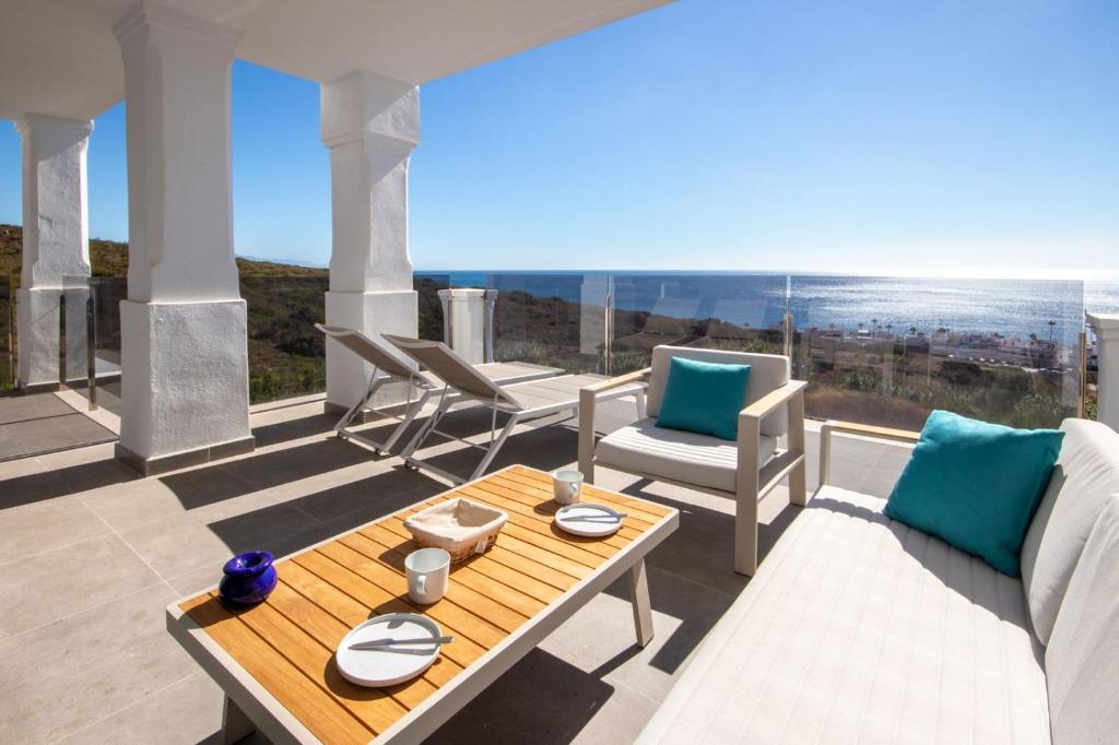 un patio con mesa, sillas y el océano en Luxury apartment with stunning sea views, en Manilva