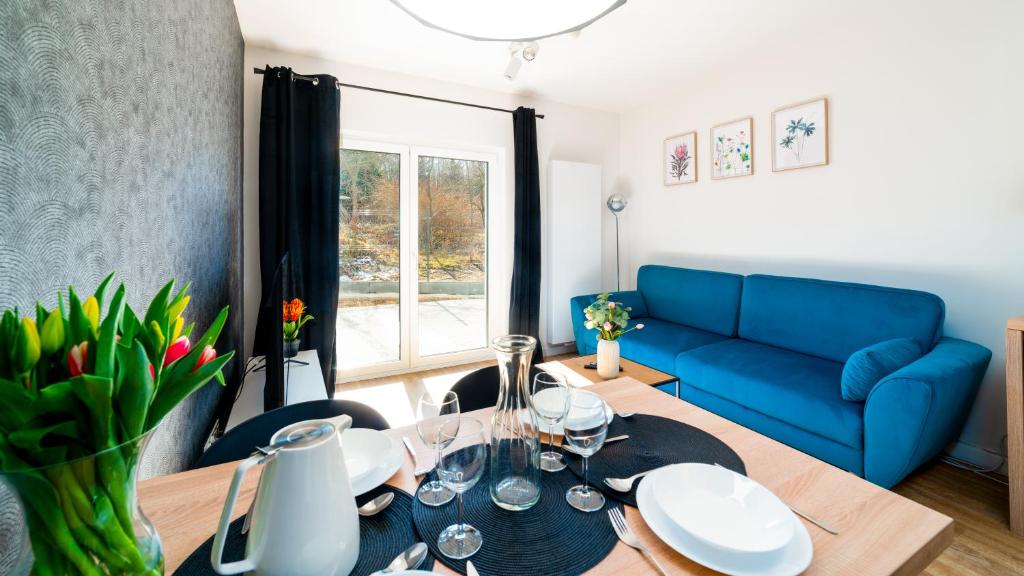 a living room with a table and a blue couch at Domki Sun & Snow Sikorskiego II in Karpacz