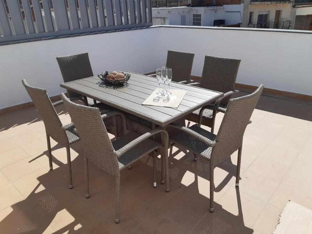 a wooden table with chairs and wine glasses on a balcony at Roses Casc Antic SL Sabater 2 in Roses