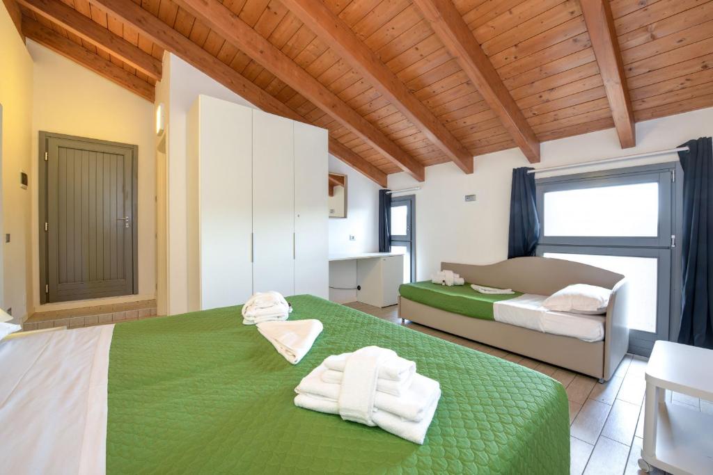 sypialnia z zielonym łóżkiem i ręcznikami na nim w obiekcie Borgo Gasparina Family Apartments w mieście Castelnuovo del Garda