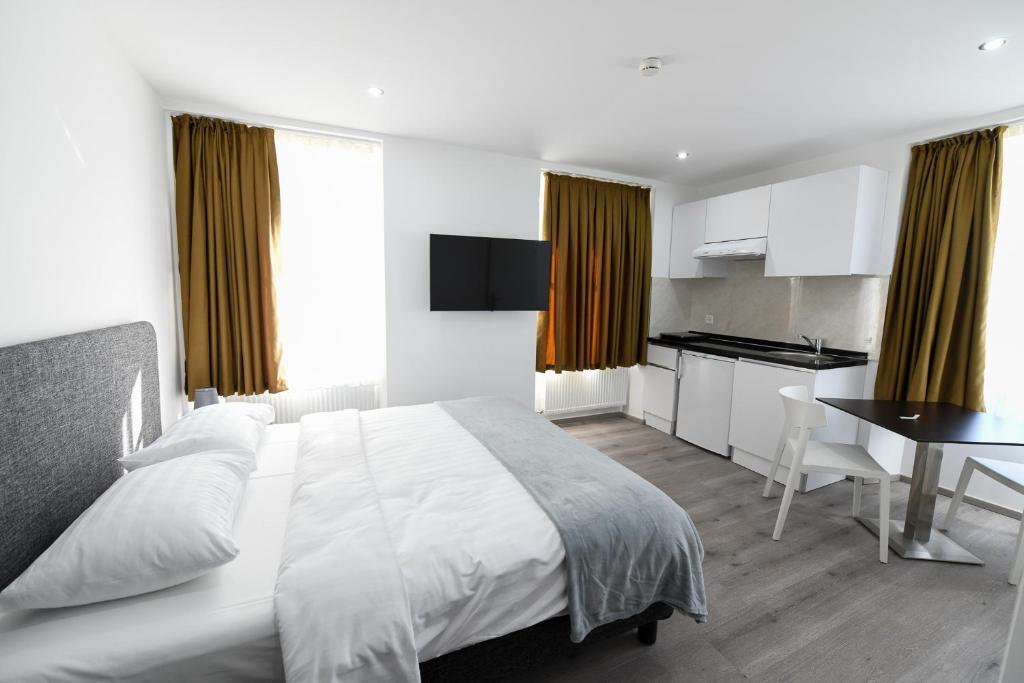 1 Schlafzimmer mit einem weißen Bett und einer Küche in der Unterkunft Hotel de France in La Chaux-de-Fonds