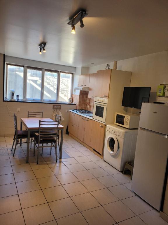 a kitchen with a table and a refrigerator and a table and chairs at CURE THERMALE OU VACANCES D'ETE AU MONT DORE in Le Mont-Dore