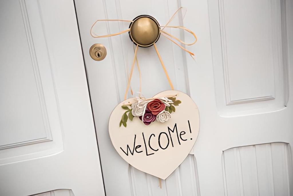 un signo de bienvenida con forma de corazón colgando de una puerta en La Foresteria - Casa Vacanze Norcia, en Norcia