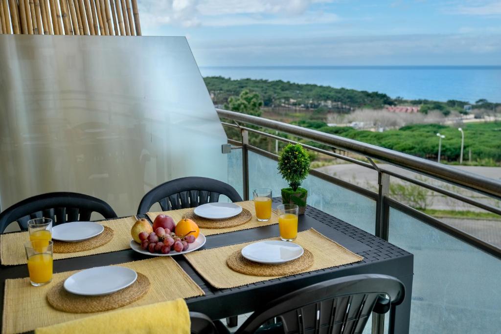 a table with fruit and glasses of orange juice on a balcony at The Family Apart Beach in Ericeira