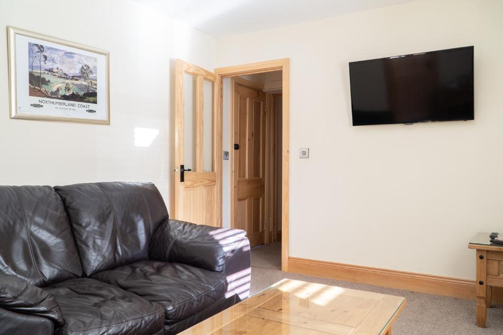 a living room with a leather couch and a coffee table at The Olde Ship Inn in Seahouses